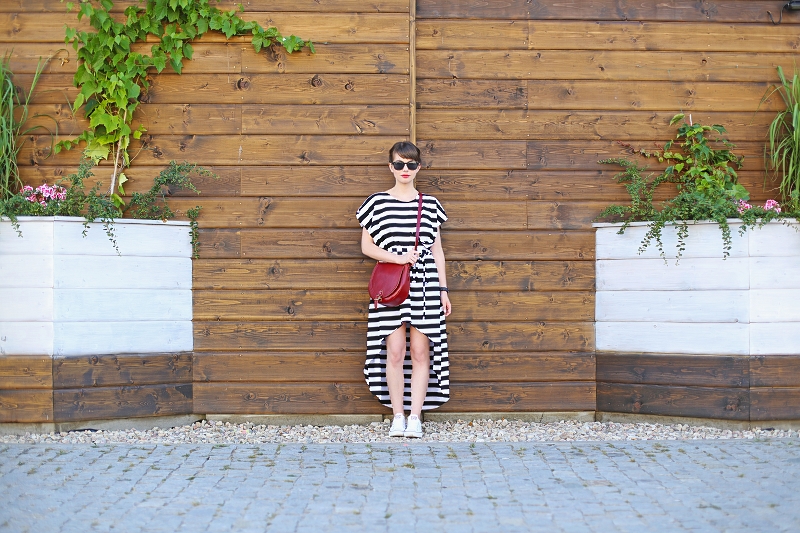 Stylizacja z pasiastą sukienką, czerwoną torebką i białymi trampkami