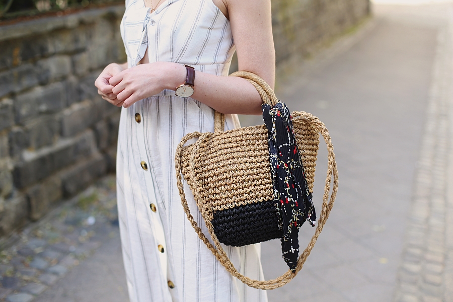 biała sukienka wiązana na biuście, naszyjnik kaskadowy, pleciona torebka